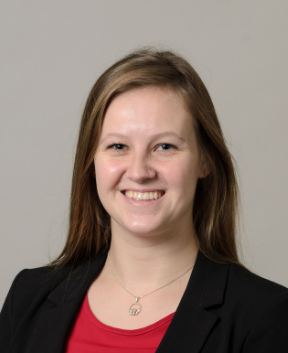 Staff member smiling at the camera in front of a grey background.