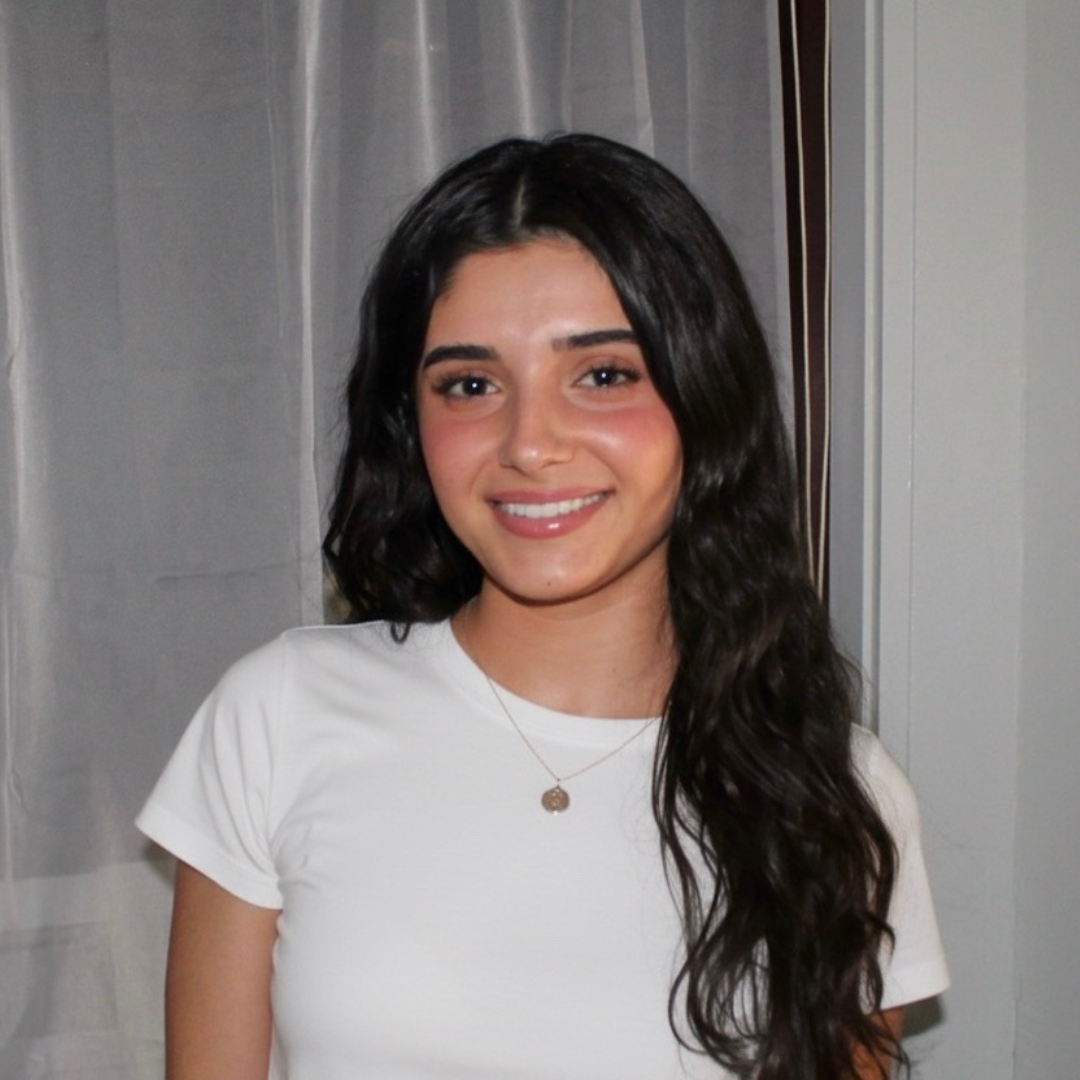 Headshot of UConn student. She has long black hair, is wearing a white t-shirt, and is smiling at the camera.