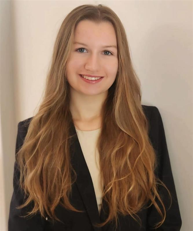 Photo of UConn student worker. She is wearing a black blazer and white blouse, and she had long blonde hair.