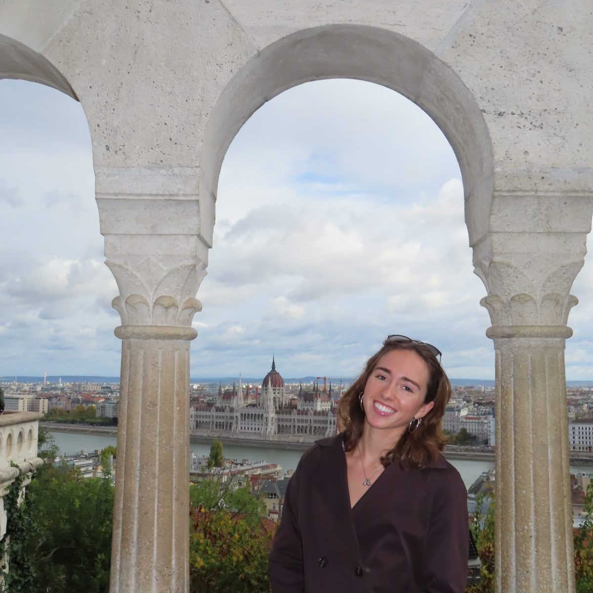 Photo of a female student smiling while sitting under an arch in Italy.
